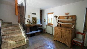 Un escalier menant à un palier où se trouvent une cheminée, un meuble en bois et une chaise.