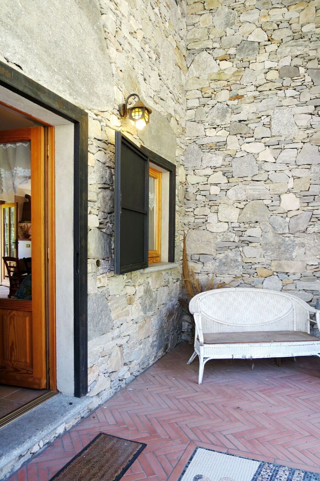 A stone-walled room with a wicker chair and a wooden door.