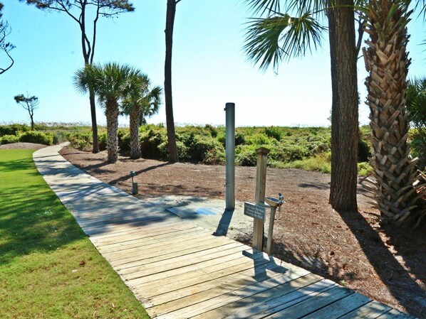A wooden boardwalk leading to a signpost with a message about food and water conservation.