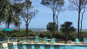 Un área junto a la piscina con sillones de descanso y vista al océano.
