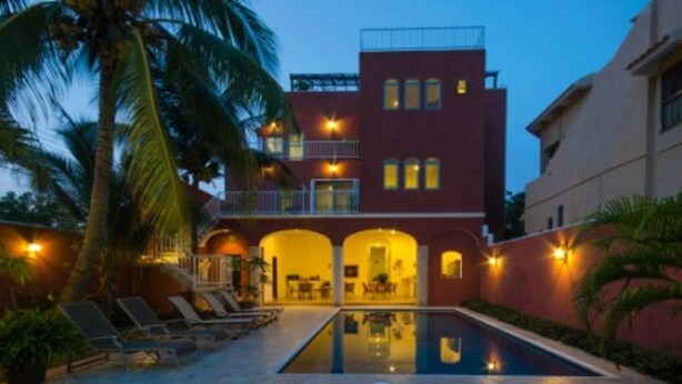 A two-story building with a swimming pool, palm trees, and outdoor seating. - Summer Place Inn Full House (San Miguel Cozumel)
