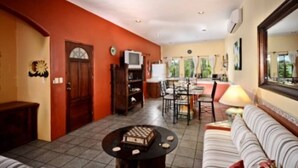 A living room with a dining area, a sofa, a TV, and a clock on the wall. - Summer Place Inn Full House (San Miguel Cozumel)