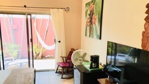 A hotel room with a bed, a TV, a coffee maker, a fan, and a chair. - Summer Place Inn Full House (San Miguel Cozumel)