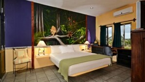 A bedroom with a bed, a desk, a chair, and a mural of a forest scene. - Summer Place Inn Full House (San Miguel Cozumel)