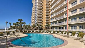 A hotel pool area with a clear blue pool, lounge chairs, and palm trees. - Gulf Views & Pool Access: Coral Reef Resort Condo (Panama City Beach)