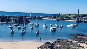 A marina with multiple boats docked, a lighthouse, and rocky shoreline. - Argo Serviced Apartments (Wollongong)