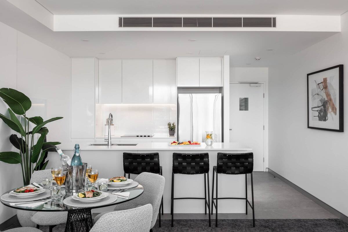 A modern kitchen with white cabinets, a central island, and bar stools.