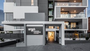 A modern multi-story building with a prominent sign for 'argó Serviced Apartments' at 65 Church Street. - Argo Serviced Apartments (Wollongong)
