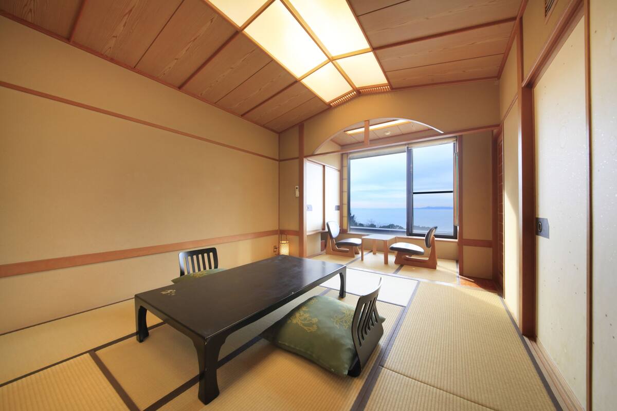 Um quarto japonês tradicional com tatames, uma mesa baixa e cadeiras.