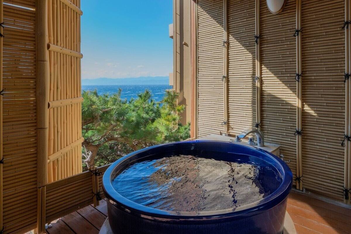 Uma banheira azul grande em um deck de madeira com vista para o oceano.