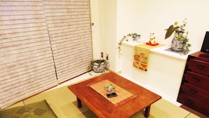 Un salon de style japonais traditionnel, avec un sol recouvert de tatamis, une basse table en bois et un paravent coulissant de type shoji.
