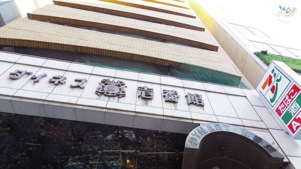 L’entrée d’un hôtel, avec une enseigne en caractères chinois et une autre indiquant « Seven & Holding ».