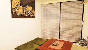Une pièce comprenant un canapé, une table en bois, un élément décoratif mural et une porte coulissante avec une fenêtre.