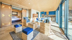 A modern interior with wooden ceilings, a kitchen area, and a living space with sofas and a bed. - Panoramia Villas (Myrtleford)