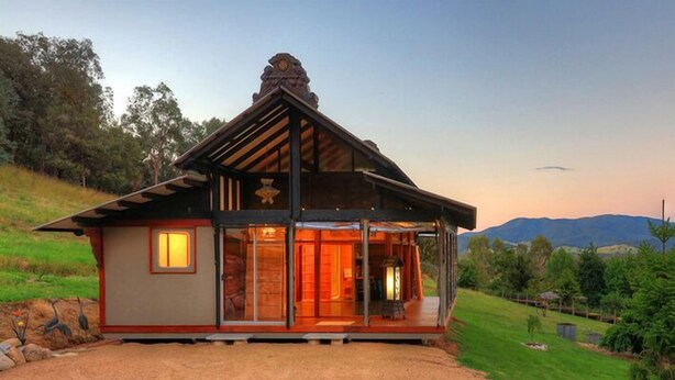A rustic lodge with a prominent entrance, a sloped roof, and a scenic view of the surrounding landscape. - Panoramia Villas (Myrtleford)