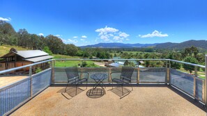 A balcony with a view of a rural landscape, including trees, hills, and a clear sky. - Panoramia Villas (Myrtleford)