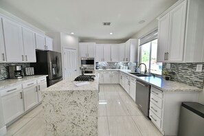 Una cocina moderna con armarios blancos, un refrigerador negro, una estufa de acero inoxidable y un respingo de azulejos.