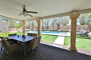 A covered patio with a pool, outdoor furniture, and a view of the backyard.