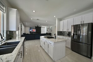 A modern kitchen with white cabinets, a stainless steel refrigerator, and a central island.