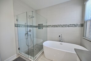 A modern bathroom with a glass-enclosed shower, a freestanding bathtub, and a tiled shower area.