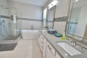 A modern bathroom with a glass-enclosed shower, a white bathtub, a vanity with a sink, and a large mirror.