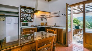 A kitchen with a wooden table, chairs, a refrigerator, a stove, and a sink. There is a window with a view of the outdoors. - Beautiful apartment for 4 guests with pool, WIFI, patio and pets allowed (Pescia)