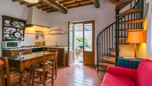 A kitchen with a wooden table and chairs, a red couch, and a spiral staircase. - Beautiful apartment for 4 guests with pool, WIFI, patio and pets allowed (Pescia)