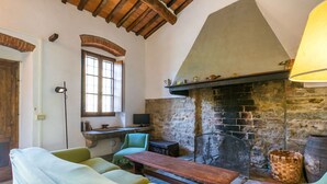 Una habitación acogedora con chimenea de piedra, vigas de madera y mobiliario tapizado en verde.