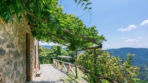 Un sentiero in pietra conduce a una struttura in legno, con vista su un paesaggio montano.