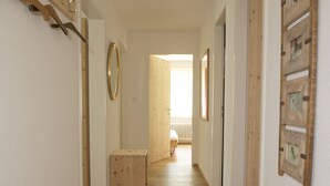 Ein Korridor mit Holzboden, einer Holzbank und einer Tür zu einem weiteren Raum.