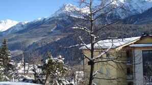 Eine Berglandschaft mit schneebedeckten Gipfeln und einem Gebäude mit gelber Fassade.