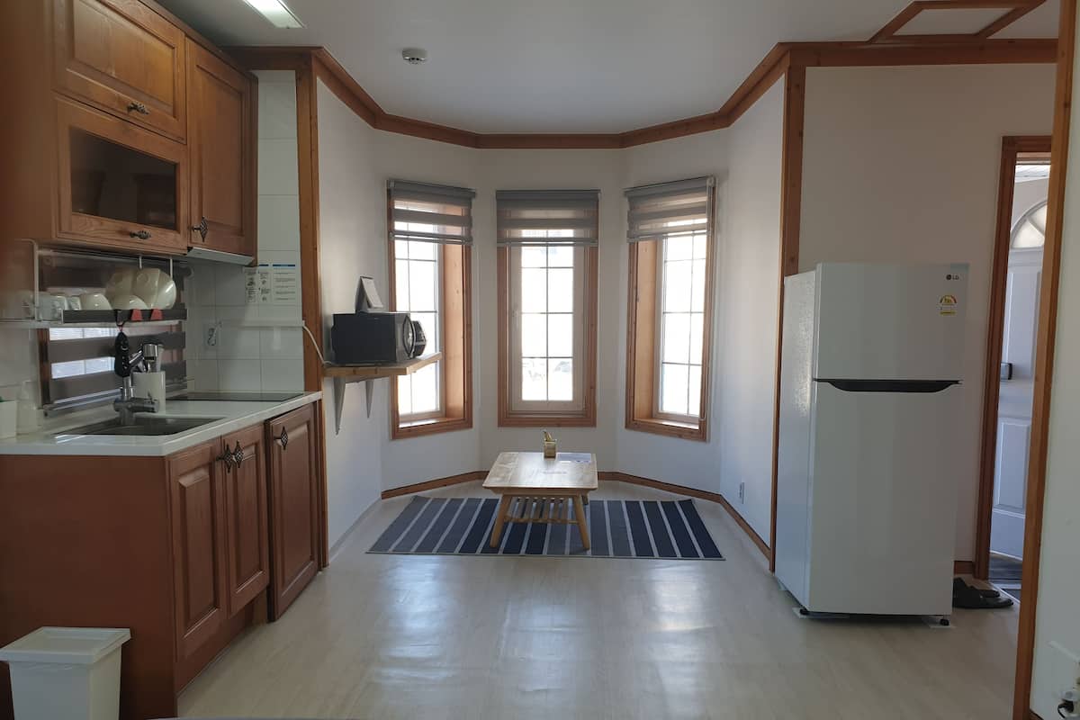 A kitchen with wooden cabinets, a white refrigerator, and a dining area with a table and bench.