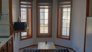 A kitchen with wooden cabinets, a countertop, a sink, and a window with a view of the outside. - Under Hill Pension (Pyeongchang)