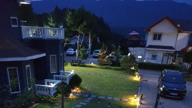 A residential area with houses, a driveway, and a circular arrangement of lights and rocks. - Under Hill Pension (Pyeongchang)