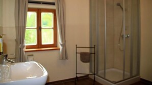 A bathroom with a white sink, a glass shower enclosure, and a window with curtains.