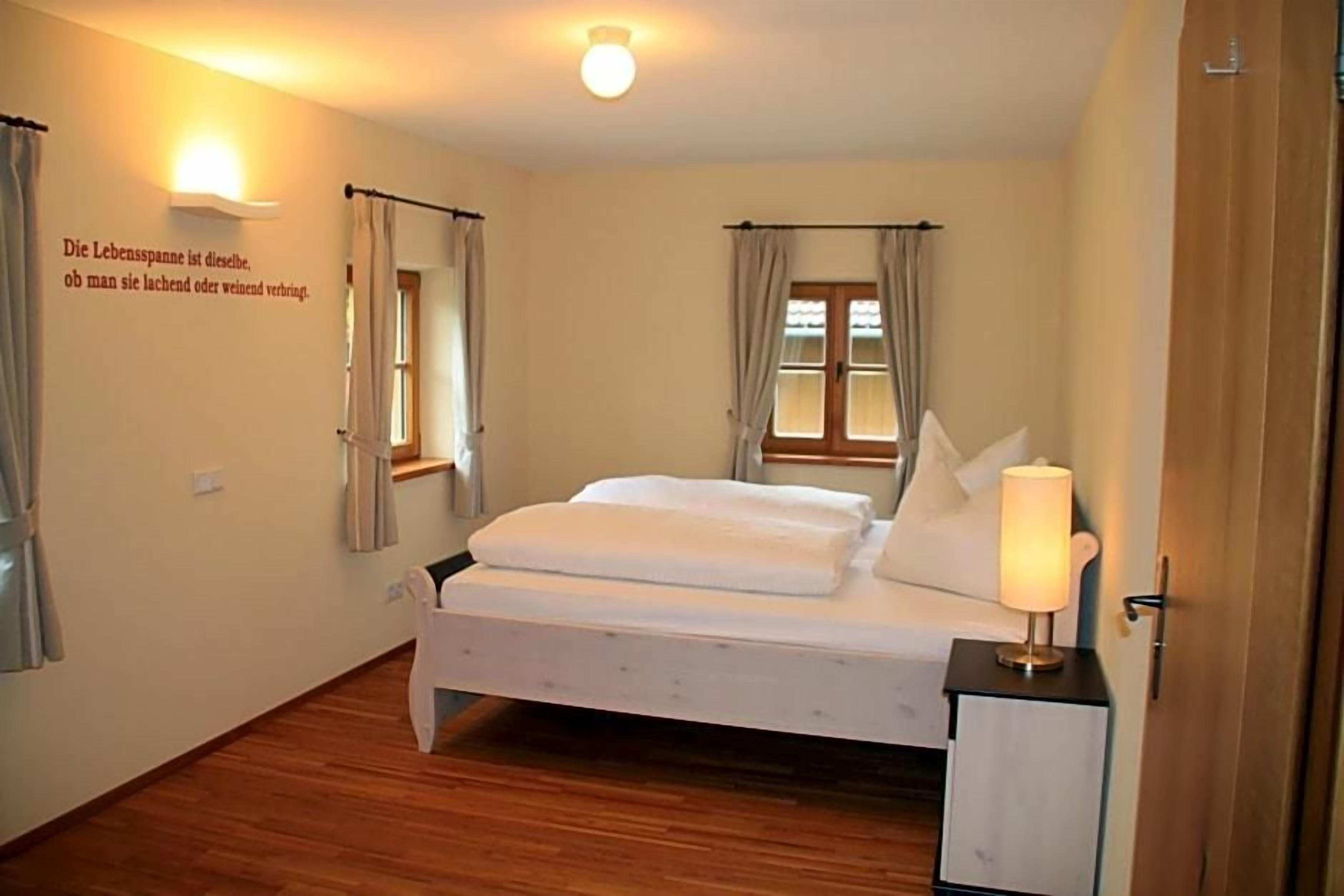 Une chambre à coucher avec un lit, une table de chevet avec une lampe et un luminaire fixé au mur.
