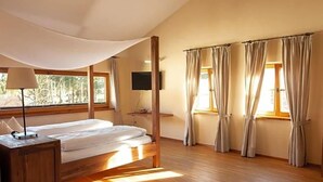 A bedroom with a bed, a TV, and curtains.