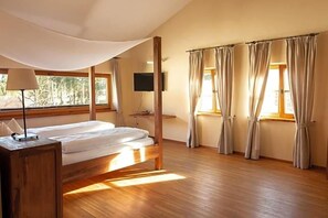 A bedroom with a bed, a TV, and curtains.