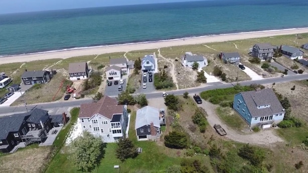 Zona residencial costera con casas, una playa y una carretera.