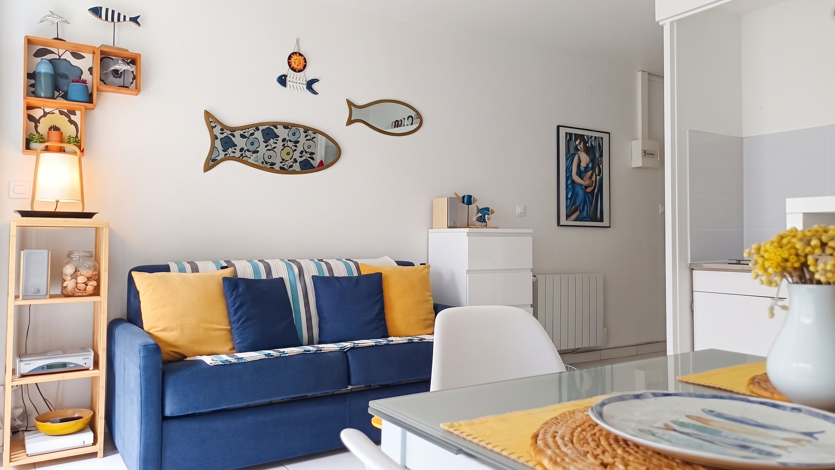 Ein modernes Wohnzimmer mit einem blauen Sofa, einem weißen Schrank und dekorativer Fisch-Wandkunst.