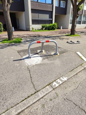A parking area with a metal barrier and a white line marking the parking space.