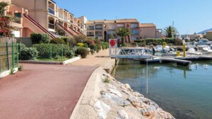 Un port de plaisance avec des bateaux, une allée rouge et des immeubles résidentiels dotés de balcons.