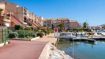 Un port de plaisance avec des bateaux, une allée rouge et des immeubles résidentiels dotés de balcons.