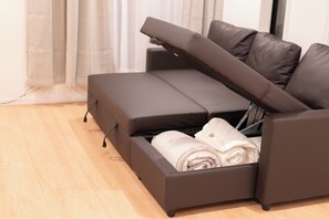 A modern sofa with a pull-out table, a built-in storage compartment, and a light-colored floor. - Satellite Hotel Yebisu (Tokyo)