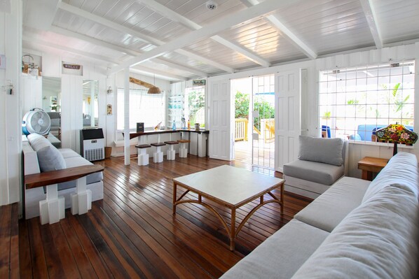A spacious living area with a wooden floor, a sofa, a coffee table, and a bar area with stools.