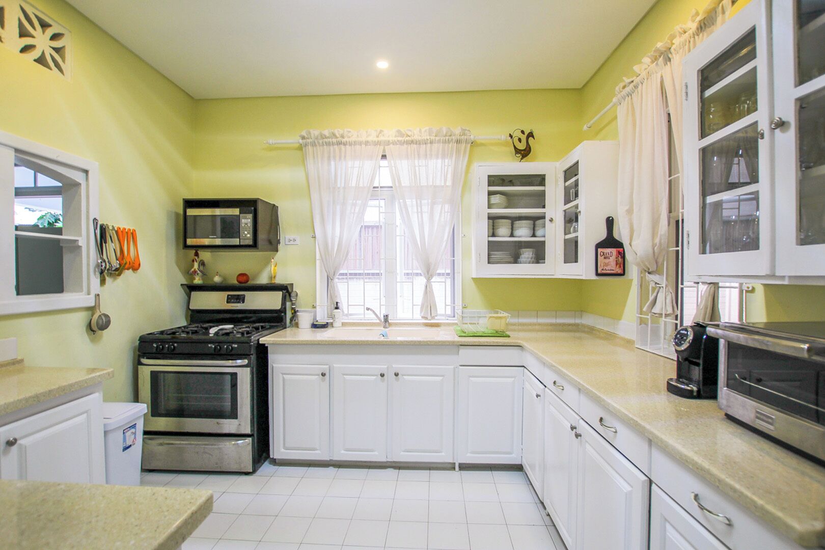 A kitchen with white cabinets, a stove, a microwave, and a coffee maker.