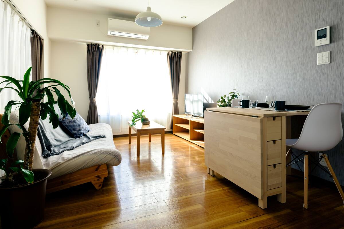 A modern living room with a wooden floor, a sofa, a desk, and a chair.