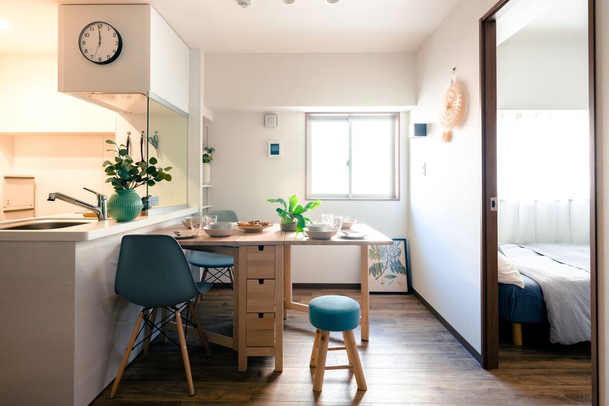 A compact kitchen with a sink, a clock, and a window.