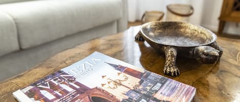 A magazine on a wooden coffee table with a decorative bowl and a sofa in the background.