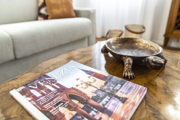 Una revista sobre una mesa de centro de madera con un cuenco decorativo y un sofá al fondo.